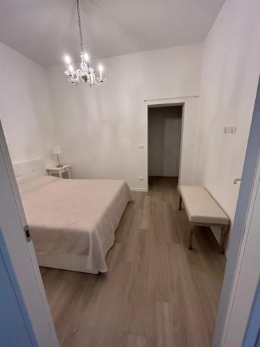 ein weißes Zimmer mit einem Bett und einem Kronleuchter in der Unterkunft bandbinbologna in Bologna