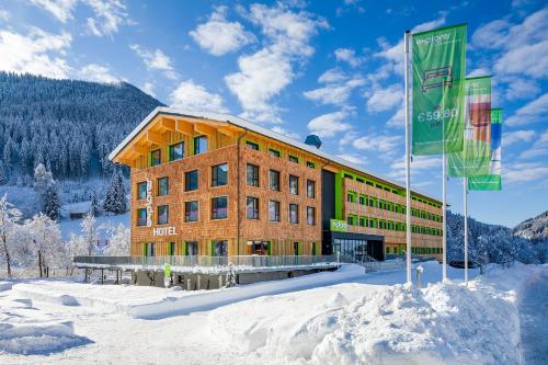 un bâtiment avec deux drapeaux dans la neige dans l'établissement Explorer Hotel Bad Kleinkirchheim, à Bad Kleinkirchheim