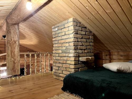 a bed in a room with a stone wall at Kaimukas - namelis prie ežero keturiems in Dvarčėnai