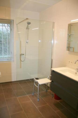 a bathroom with a shower and a sink and a chair at Crox Houcke 65 in Nieuwvliet