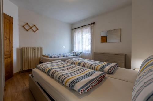 Cette chambre comprend 3 lits avec des oreillers rayés. dans l'établissement Appartamento Lärchenwald - Trepalle, à Livigno