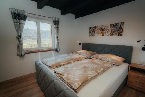 a bed in a bedroom with a large window at Bergblickapartments in Spital am Pyhrn