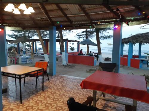 a restaurant with tables and chairs on the beach at One Love Beach Bar in Ghana Town