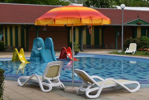 センテシュにあるSzentesi Sport- és Üdülőközpontのスイミングプールの隣に椅子とパラソル付きのプールがあります。