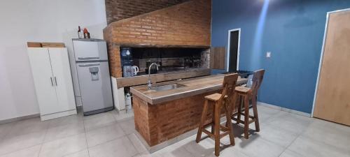eine Küche mit einer Spüle und einer Theke mit Stühlen in der Unterkunft Quinta Loma Hermosa in Diamante