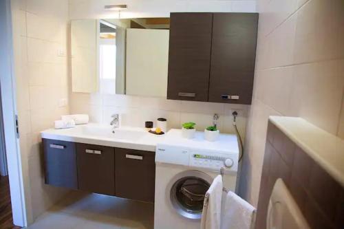 uma casa de banho com uma máquina de lavar roupa e um lavatório em TOP BELLAVISTA MOLVENO em Molveno