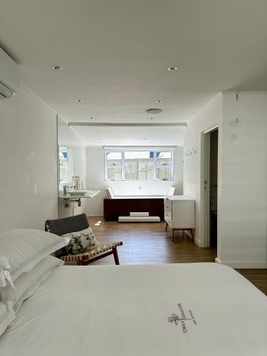 a white bedroom with a bed and a bathroom at Riebeeck Villa - 5 min walk to Franschhoek Central in Franschhoek