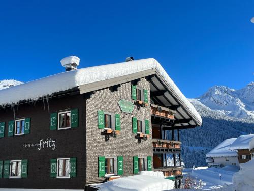 a building with green shuttered windows in the snow at Gästehaus Fritz in Mittelberg