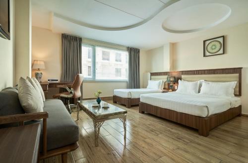 um quarto de hotel com duas camas e um sofá em Sky Gem Hotel - Ben Thanh em Ho Chi Minh