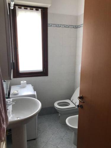 La salle de bains est pourvue de toilettes, d'un lavabo et d'une fenêtre. dans l'établissement Appartamento comodo per brevi periodi, à Forlì