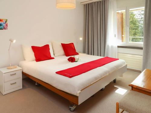 a bedroom with a large bed with red pillows at Apartment Allod-Park-57 by Interhome in Davos