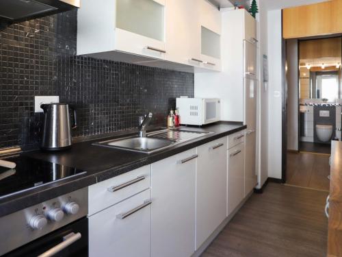 a kitchen with white cabinets and a sink at Apartment Allod Park Haus C 605 by Interhome in Davos