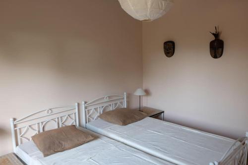 een wit bed met 2 kussens in een slaapkamer bij Villa avec piscine près de l'océan. in Cap Skirring