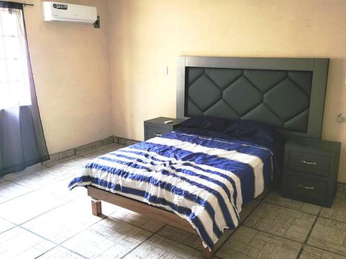 a bedroom with a bed with a blue and white comforter at Hermosa Casa en Cuatro ciénegas in Cuatrociénegas de Carranza
