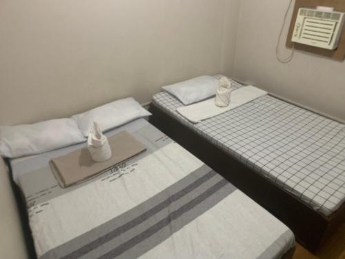 two twin beds in a small room with towels at Full Moon Hostel - Beer Pong Central in Coron