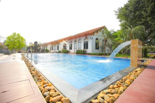 a swimming pool with a fountain in front of a house at Hoa Lu Garden Resort in Ninh Binh
