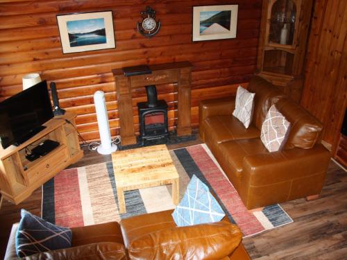 a living room with a couch and a wood stove at Chalet Highand Lodges-1 by Interhome in Spean Bridge