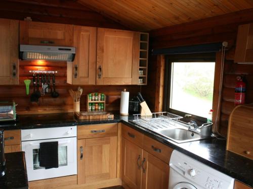 a kitchen with wooden cabinets and a sink and a window at Chalet Highand Lodges-1 by Interhome in Spean Bridge