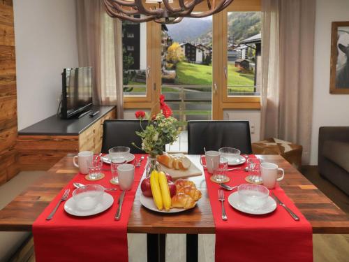 a table with a red table cloth and fruit on it at Apartment Papillon by Interhome in Zermatt