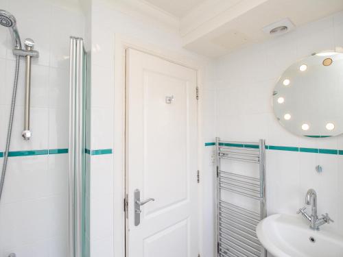 a bathroom with a shower and a sink and a mirror at Sandy Haven in Swanage