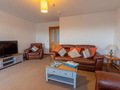 a living room with a leather couch and a tv at Holiday Home Shedfield by Interhome in Drumnadrochit
