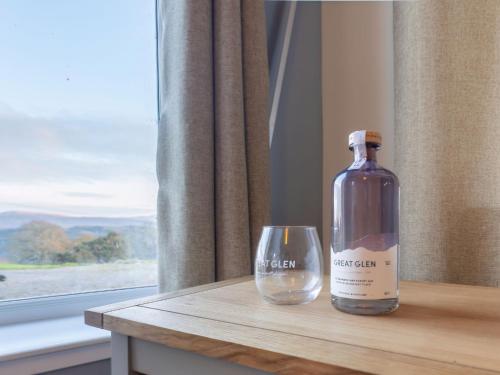 una botella de vino sentada en una mesa junto a una copa en Holiday Home Shedfield by Interhome en Drumnadrochit