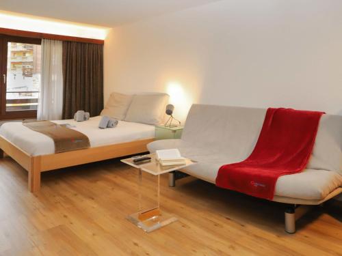 Un dormitorio con una cama, un sofá y una silla. en Apartment Pasadena-3 by Interhome, en Zermatt