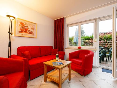 a living room with a red couch and two chairs and a table at Holiday Home Susi by Interhome in Ostseebad Koserow