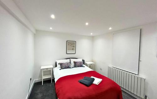 um quarto com uma cama vermelha e branca e uma janela em London Mitcham Beautifully Presented Two Bedroom Apartment em Mitcham