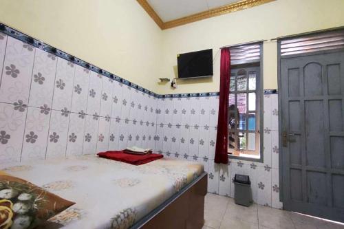 Cette chambre comprend un lit, une fenêtre et une porte. dans l'établissement OYO 93396 Pondok Wisata Sri Mulyo, à Yogyakarta