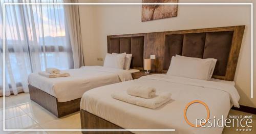 Dos camas en una habitación de hotel con toallas. en luxury apartments in cairo , porto new cairo , nyum, en El Cairo