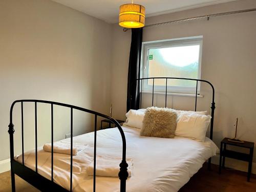 Pass the Keys Charming Guest House in St Albans with Parking في سانت ألبانز: غرفة نوم بسرير أسود ومخدات بيضاء ونافذة