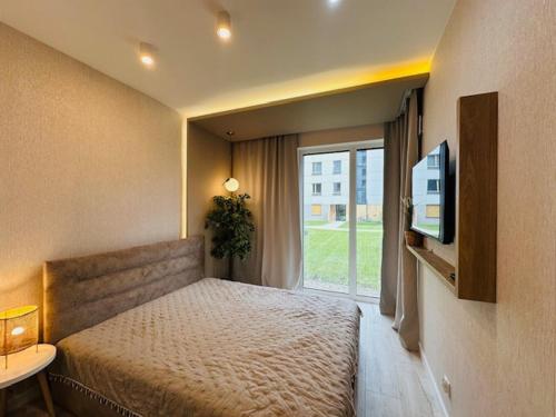 sypialnia z łóżkiem, telewizorem i oknem w obiekcie Apartamenty Sun & Snow Polanka Niemena w Poznaniu