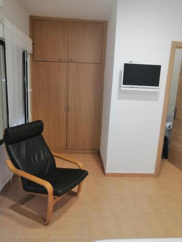 Cette chambre comprend une chaise noire et une télévision murale. dans l'établissement La Callejuela Balcón, à Villarejo de Salvanés