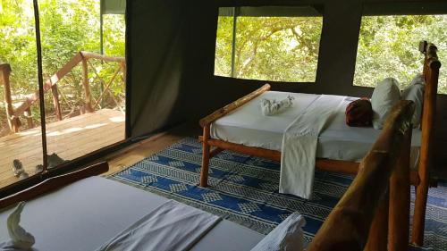 a bedroom with a bed in a tent with a porch at Camp Seluu - Safari Pkg in Kwangwazi