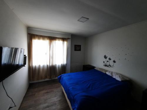 - une chambre avec un lit bleu et une fenêtre dans l'établissement Esmeralda casa de Mar, à Camet Norte