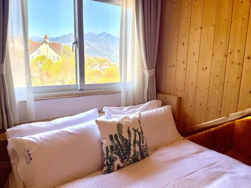 仁愛鄉的住宿－印象北歐莊園俱樂部，窗户间内的一张带枕头的床