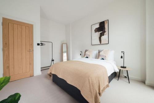a white bedroom with a bed and a wooden door at Light & Luxury London Apartment in Honor Oak in London