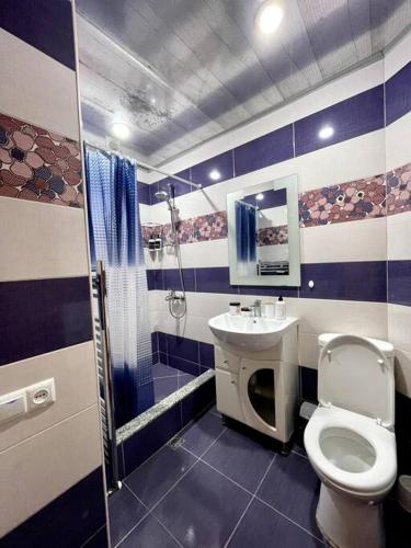 La salle de bains bleue et blanche est pourvue de toilettes et d'un lavabo. dans l'établissement Sunny 2-Bedroom Flat in Yerevan., à Erevan