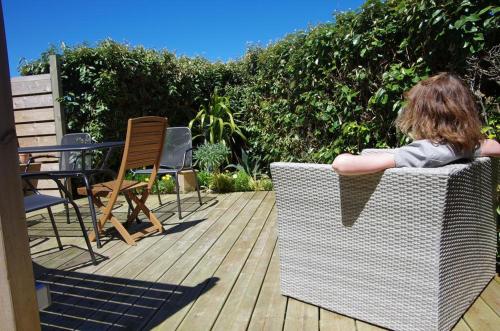 a woman sitting in a wicker chair on a deck at Maner an Aod in Plouescat