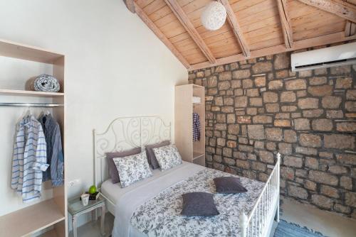 a bedroom with a bed and a stone wall at AGROTOPIA Guesthouses in Theologos
