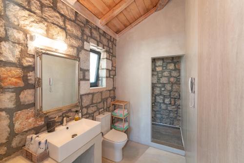 un bagno in pietra con lavandino e specchio di AGROTOPIA Guesthouses a Theologos