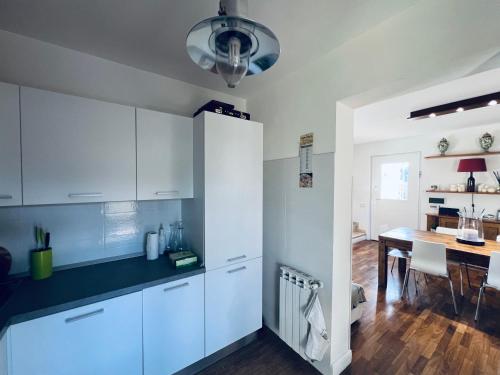 a kitchen with white cabinets and a dining table at Casa Luca 1C in Sasso