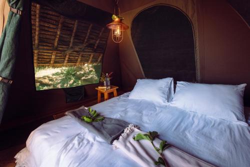 Un dormitorio con una cama con sábanas blancas y plantas. en Maji Moto Eco Camp, en Maji Moto