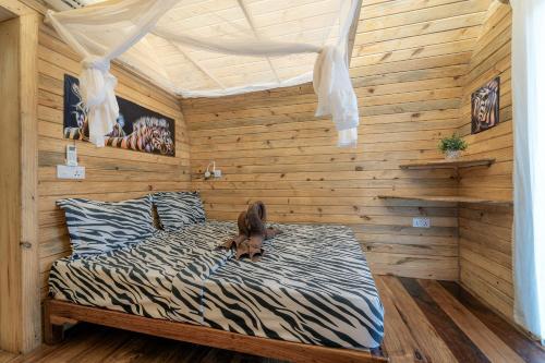 a dog laying on a bed in a room with wooden walls at Makofi Guest House in Nungwi