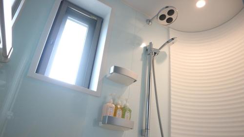 a bathroom with a shower with a window and bottles at Little Mermaid Hotel Ishigakijima in Ishigaki Island