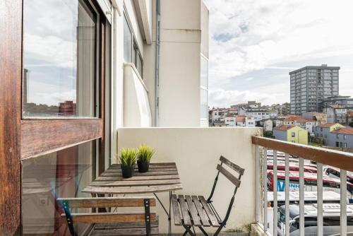 einen Balkon mit einer Holzbank und einem Tisch in der Unterkunft Pratinhas in Porto