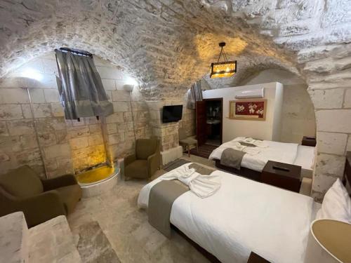 Habitación de hotel con 2 camas y pared de piedra. en Muzepotamia Butik Otel en Sanlıurfa