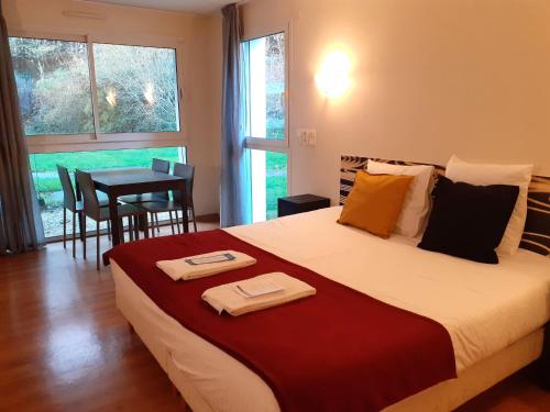 La Villa des Golf.e.s في Theix: غرفة نوم بسرير كبير وطاولة مع كراسي