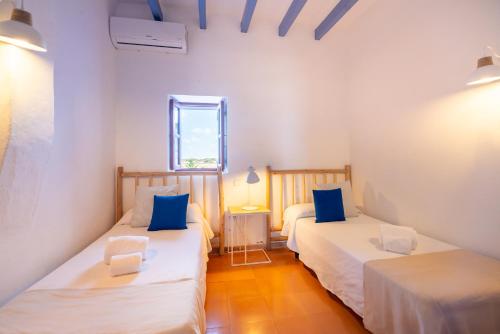 two beds in a room with white walls and blue pillows at Cas Saliners - Ses Illetes in La Savina